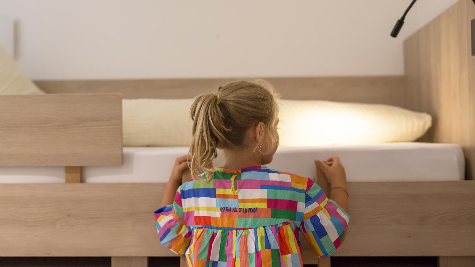 A girl is going up on the bed at Hotel Maibad in Vipiteno