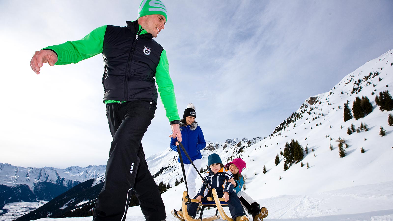 A family enjoys a sledge ride on the slopes near the Hotel Maibad